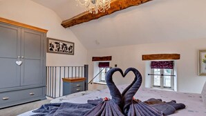 Ein Schlafzimmer mit einem Bett, einer Kommode, einer Chandelüster und einer herzförmigen Handtuchgestaltung.