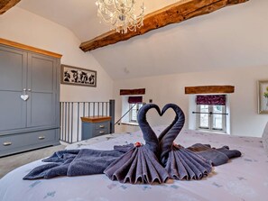 A bedroom with a bed, a dresser, a chandelier, and a heart-shaped towel arrangement. - 1 Bed in Matlock (oc-75400) (Middleton)
