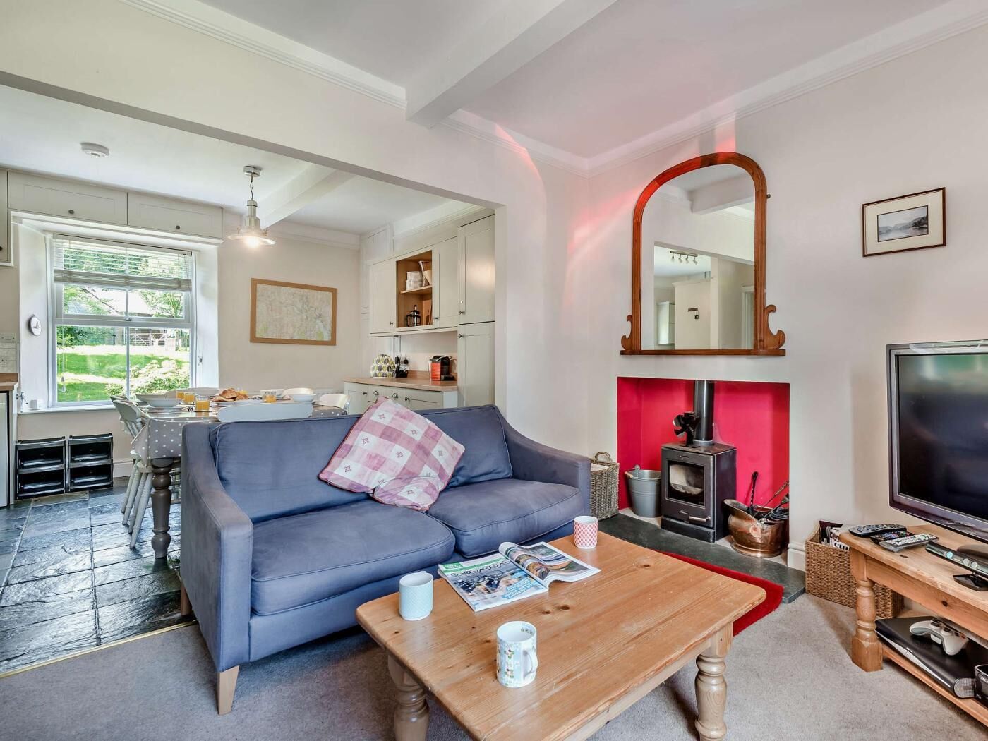 A living room with a sofa, coffee table, TV, fireplace, and kitchen area.