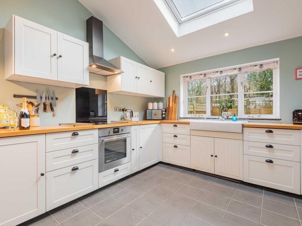 A kitchen with white cabinets, a black stove, and a window with a view of greenery.