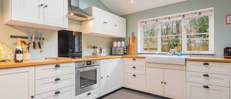 A kitchen with white cabinets, a black stove, and a window with a view of greenery.