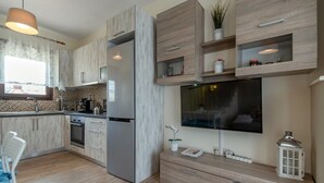 Una cucina moderna con frigorifero, piano cottura e forno a microonde integrati. È presente un'area pranzo con tavolo e sedie, e un'ampia finestra che offre luce naturale.