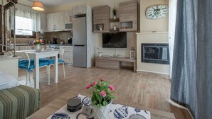 Una cucina moderna con frigorifero integrato, un'area pranzo con tavolo e sedie bianche, una TV a schermo piatto e un camino.