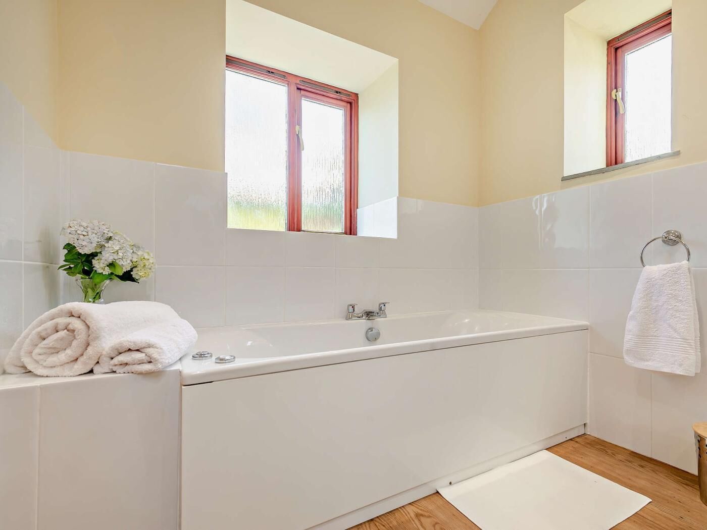 A modern bathroom with a bathtub, a window, and a mirror.