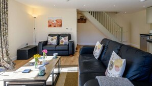 Ein modernes Wohnzimmer mit einer Couch, einem Couchtisch und einer Treppe, die in eine Küche führt.