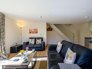 Ein modernes Wohnzimmer mit einer Couch, einem Couchtisch und einer Treppe, die in eine Küche führt.