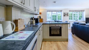 Eine moderne Küche mit Kochinsel, Backofen und Essbereich mit einer Couch.