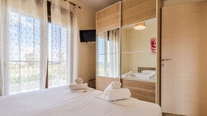 Habitació d'hotel amb un llit, un mirall gran, una televisió i un armari.