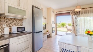 Cuina moderna amb frigorífic, microones i zona de dinar amb taula i cadires.