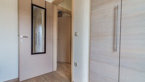 Un passadís amb una porta de fusta, un mirall i un armari.