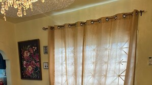 Un sofá verde con cojines con forma de corazón, una araña y un cuadro floral en la pared.