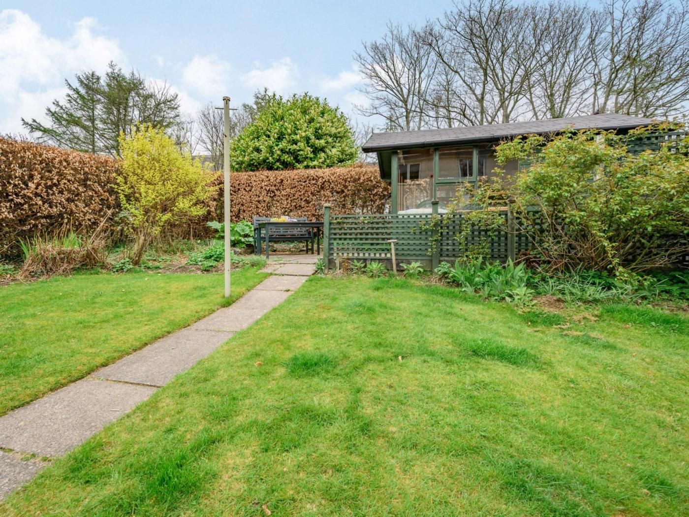 A pathway leading to a house with a fenced garden area.