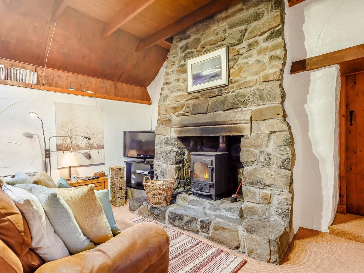 A cozy living room with a stone fireplace, a television, and a comfortable sofa.