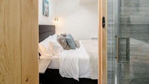 Una camera da letto con un letto, una testiera, una lampada a parete e un quadro.