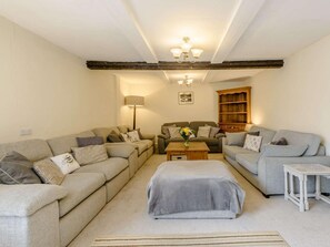 Ein Wohnzimmer mit zwei Sofas, einem Couchtisch, einer Lampe und einem Bücherregal.