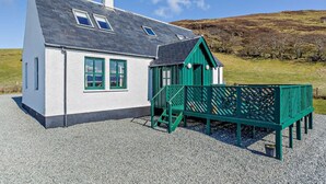 A white building with a grey roof, green windows, and a green structure with a ramp. - 3 Bed in Isle Of Skye (oc-ca071) (Aird of Sleat)