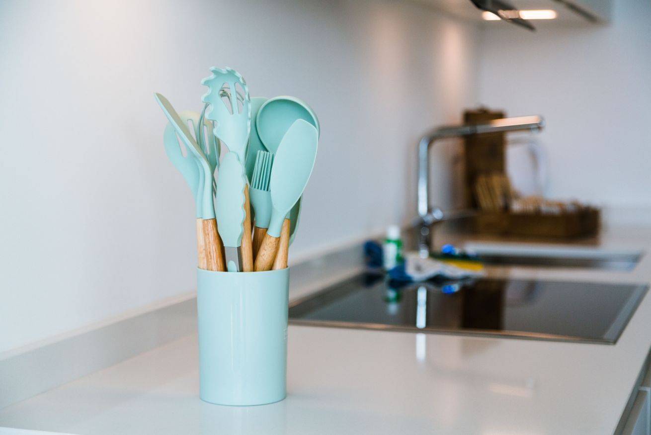 Una cucina con un portauensili azzurro chiaro contenente utensili con manici in legno.