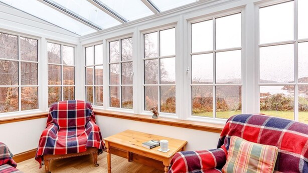 A conservatory with a wooden bench, a sofa, and a table with a book and a cup. - 6 Bed in Lairg (oc-ca210) (Laxford Bridge)