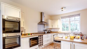 A modern kitchen with built-in ovens, a large window, and a bar area. - 6 Bed in Lairg (oc-ca210) (Laxford Bridge)