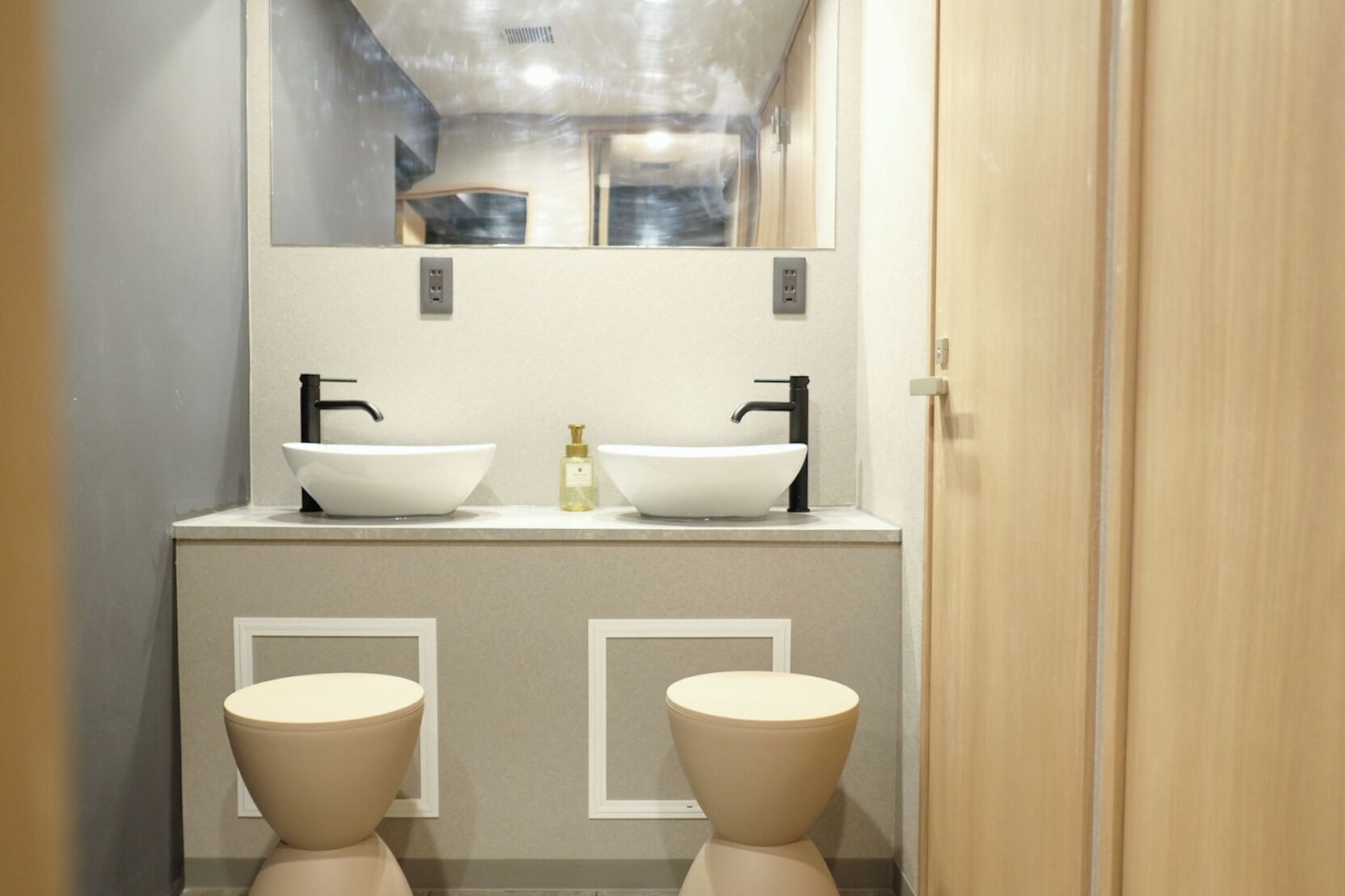 Un bagno con due lavabi, uno specchio e due servizi igienici.