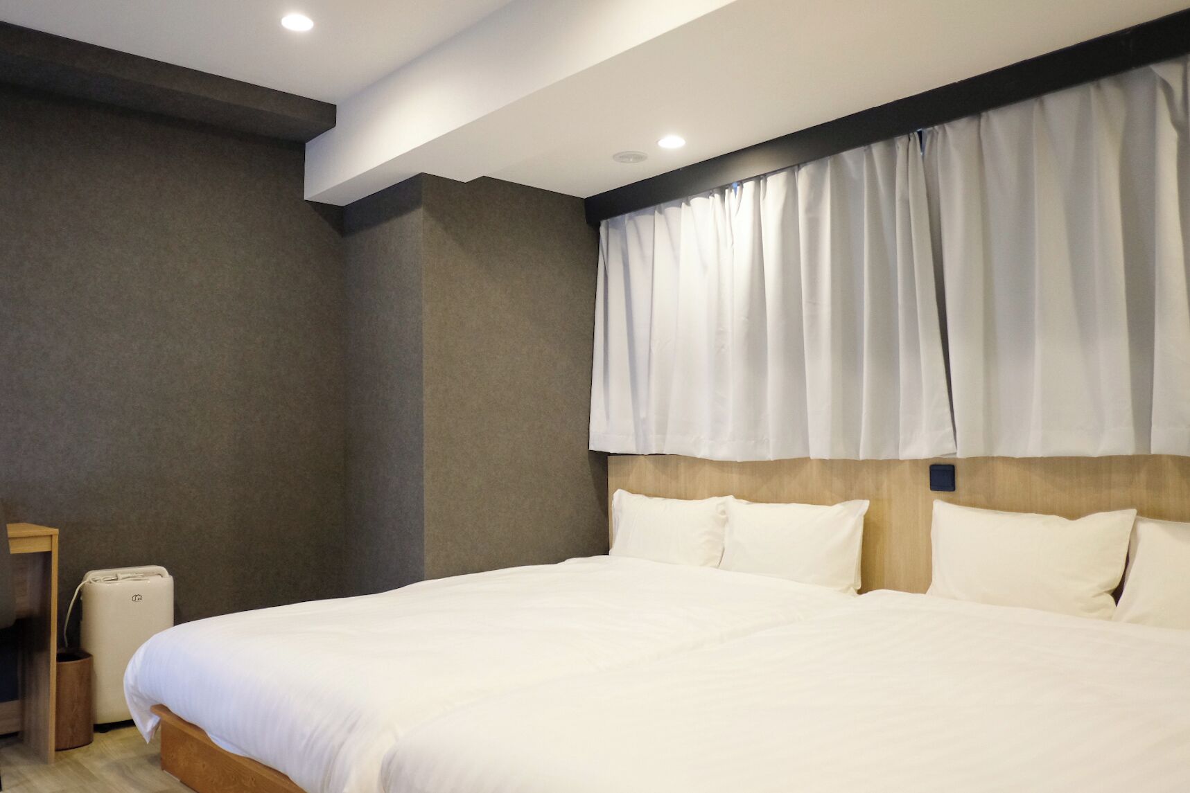 A hotel room with a large bed, a wooden headboard, and a bedside table.