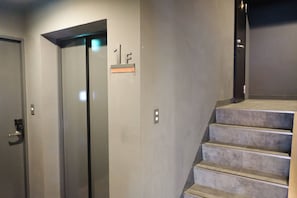 An elevator, a staircase, and a door with a number plate. - LUMA URBAN HOTEL TAKADANOBABA (Tokyo)