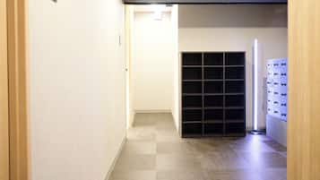 A hallway with a checkered floor, a door frame, a light switch, and a wall-mounted storage unit.