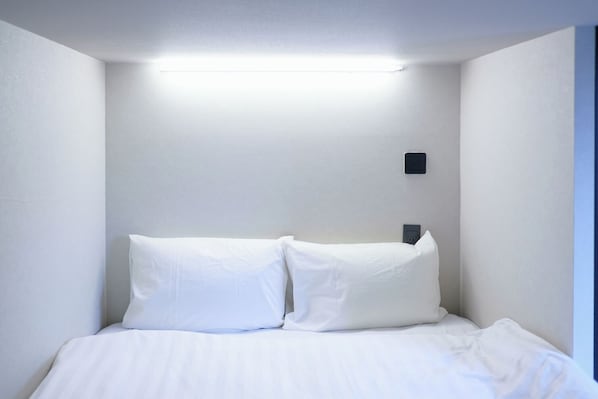 A single bed with white bedding in a room with white walls and a ceiling light. - LUMA URBAN HOTEL TAKADANOBABA (Tokyo)
