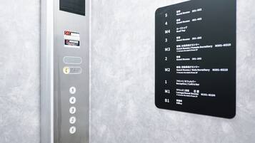 Ein Bedienfeld einer Aufzugskabine mit digitaler Anzeige und einem an der Wand befestigten Verzeichnis, das Stockwerke und deren Annehmlichkeiten auflistet.