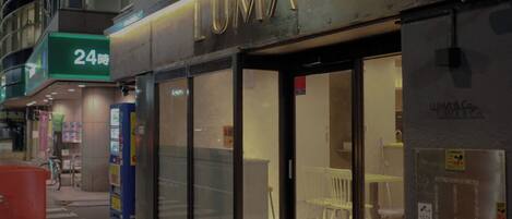 A storefront with a sign reading 'LUMA' and a 24-hour service sign.