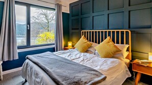 A bedroom with a bed, a bedside table, a lamp, a window with curtains, and a view of the outdoors. - 3 Bed in Pitlochry (oc-ca207) (Tressait)