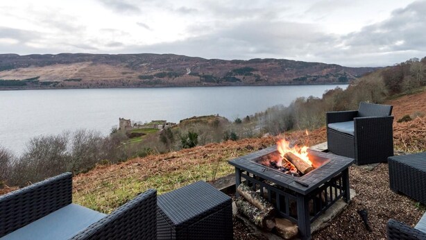 A lakeside view with outdoor seating and a fire pit. - 2 Bed in Drumnadrochit (oc-ca315) (Strone)