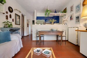 Un espacio habitable compacto con cocina, comedor y zona de estar con sofá y mesa de centro.