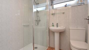 A bathroom with a glass-enclosed shower, a pedestal sink, and a toilet.