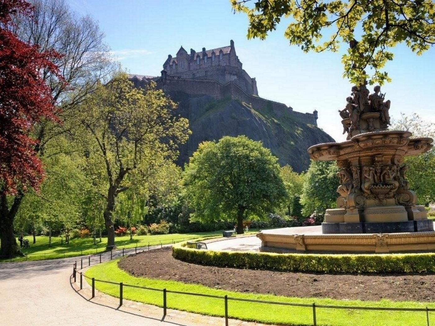 A castle in the background, a fountain in the foreground, and a pathway leading to the castle.