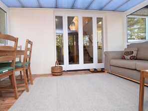 Ein gemütliches Wohnzimmer mit einer Couch, einem Esstisch mit Stühlen und einer Glastür, die zu einer Treppe führt.