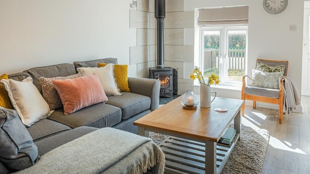 Ein Wohnzimmer mit Sofa, Couchtisch, Sessel, Kamin und einem Fenster mit Aussicht.