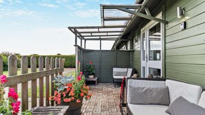 Un patio techado con cerco de madera, mobiliario exterior y plantas en macetas.