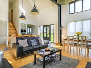 A modern living room with a sofa, coffee table, and dining area. - 3 Bed in Chulmleigh (oc-65743) (Ashreigney)