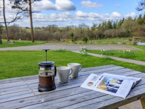 A wooden table with a French press coffee maker, two white mugs, and a newspaper. - 3 Bed in Chulmleigh (oc-65743) (Ashreigney)
