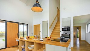 Eine moderne Küche mit einer zentralen Kochinsel, Holzböden und einer Treppe, die in eine andere Ebene führt.