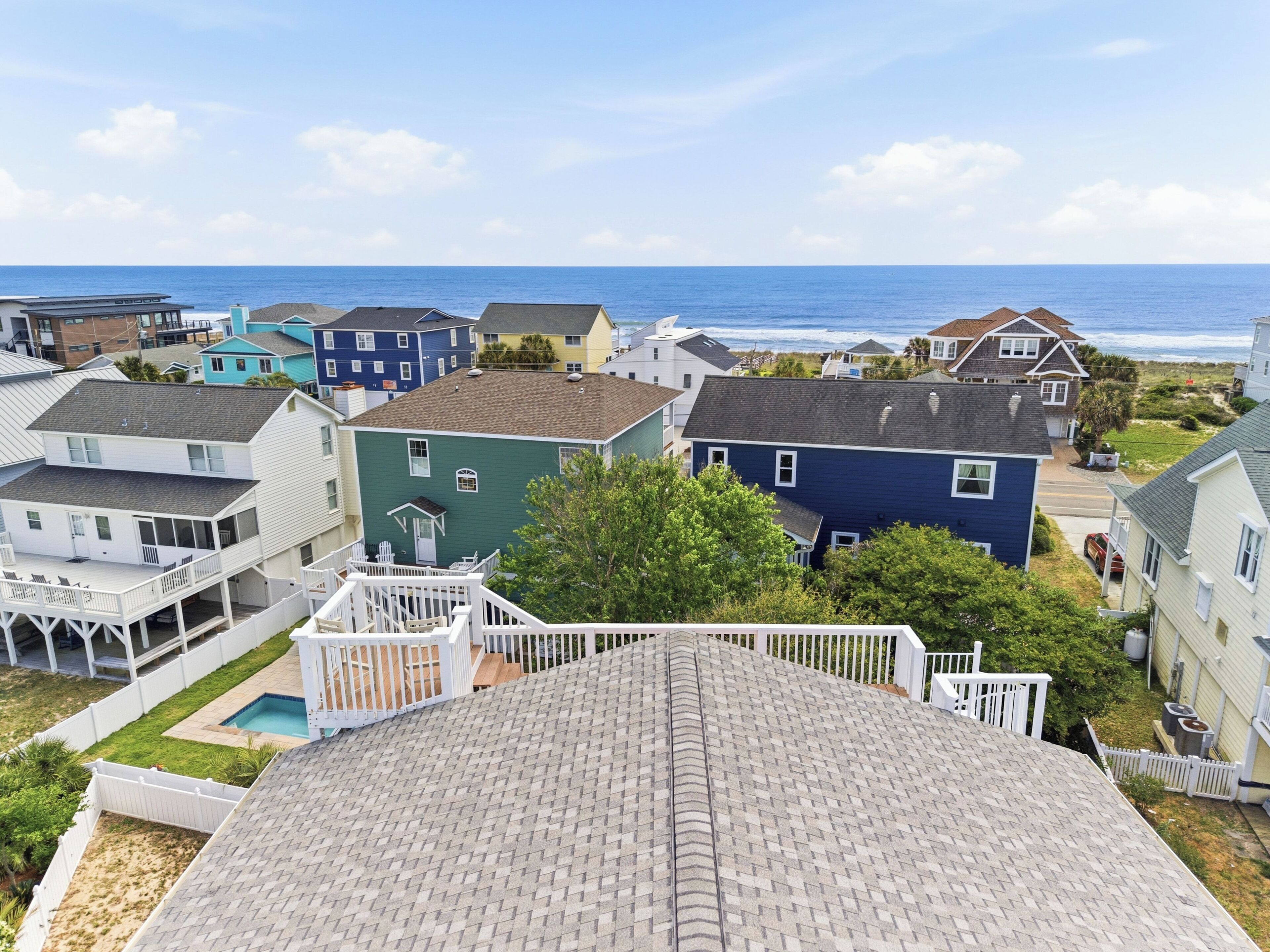 Uma área residencial costeira com casas, piscina e vista para o oceano.