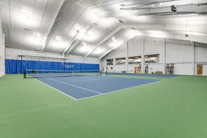 An indoor tennis court with a net, blue and green flooring, and a high ceiling with exposed beams and lighting fixtures. - Sea Colony - 55110 Manor Pl. (Bethany Beach)