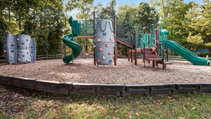 Un parque infantil con estructuras para escalar, toboganes y un banco de madera.