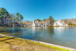 A lakeside hotel with multiple buildings, a wooden dock, and a clear sky. - Sea Colony - 55110 Manor Pl. (Bethany Beach)