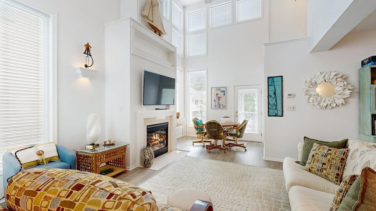 A spacious living room with a fireplace, a television, and a dining area with chairs.
