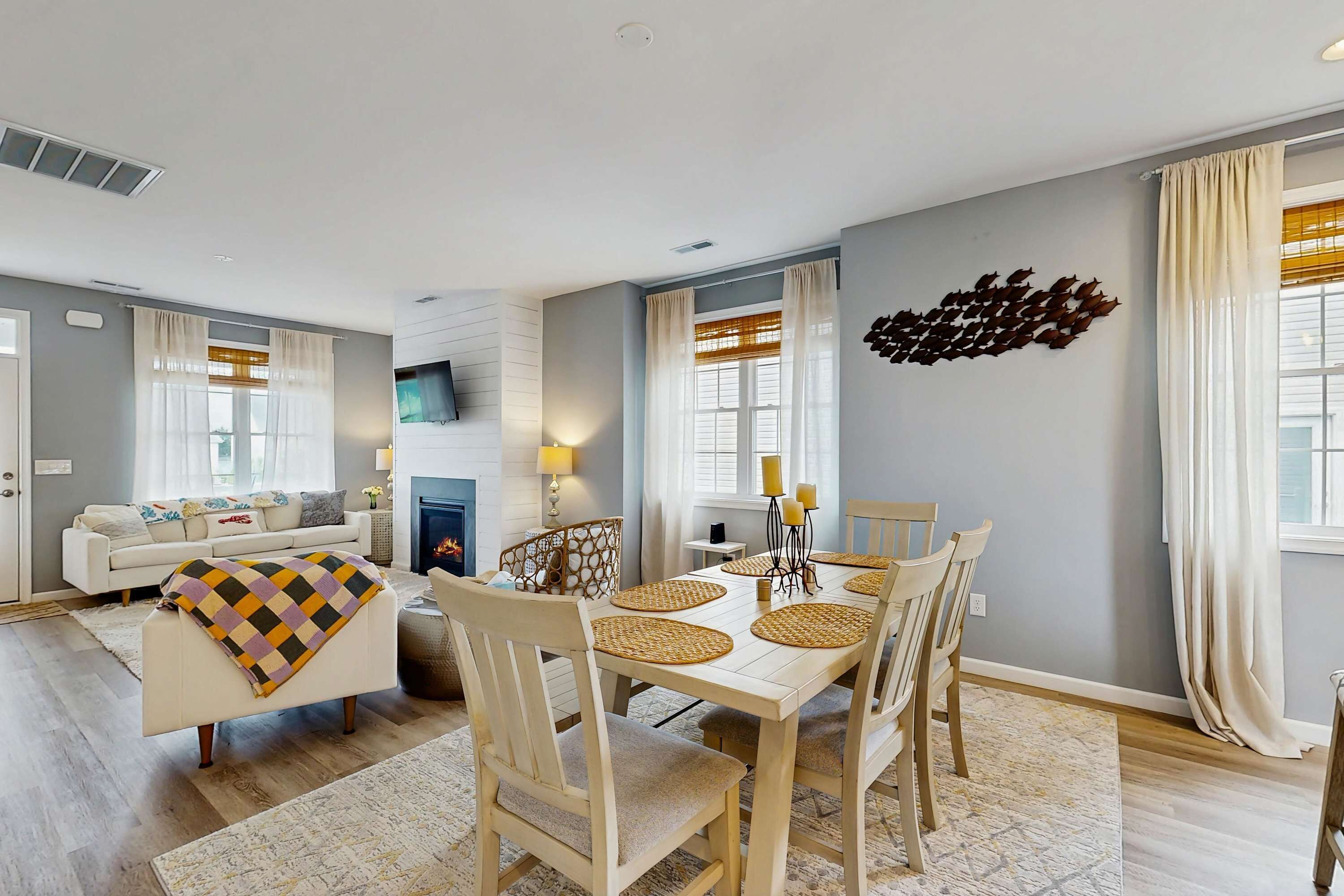A dining area with a white table, four chairs, and a decorative wall piece.
