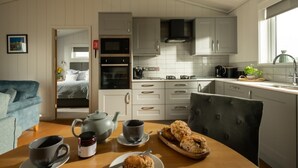 Een moderne keuken met witte kastjes, een ingebouwde oven en een koffiezetapparaat.