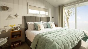 Een slaapkamer met een bed, nachtkastje en raam met uitzicht.