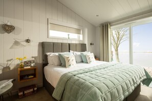A bedroom with a bed, bedside table, and a window with a view.